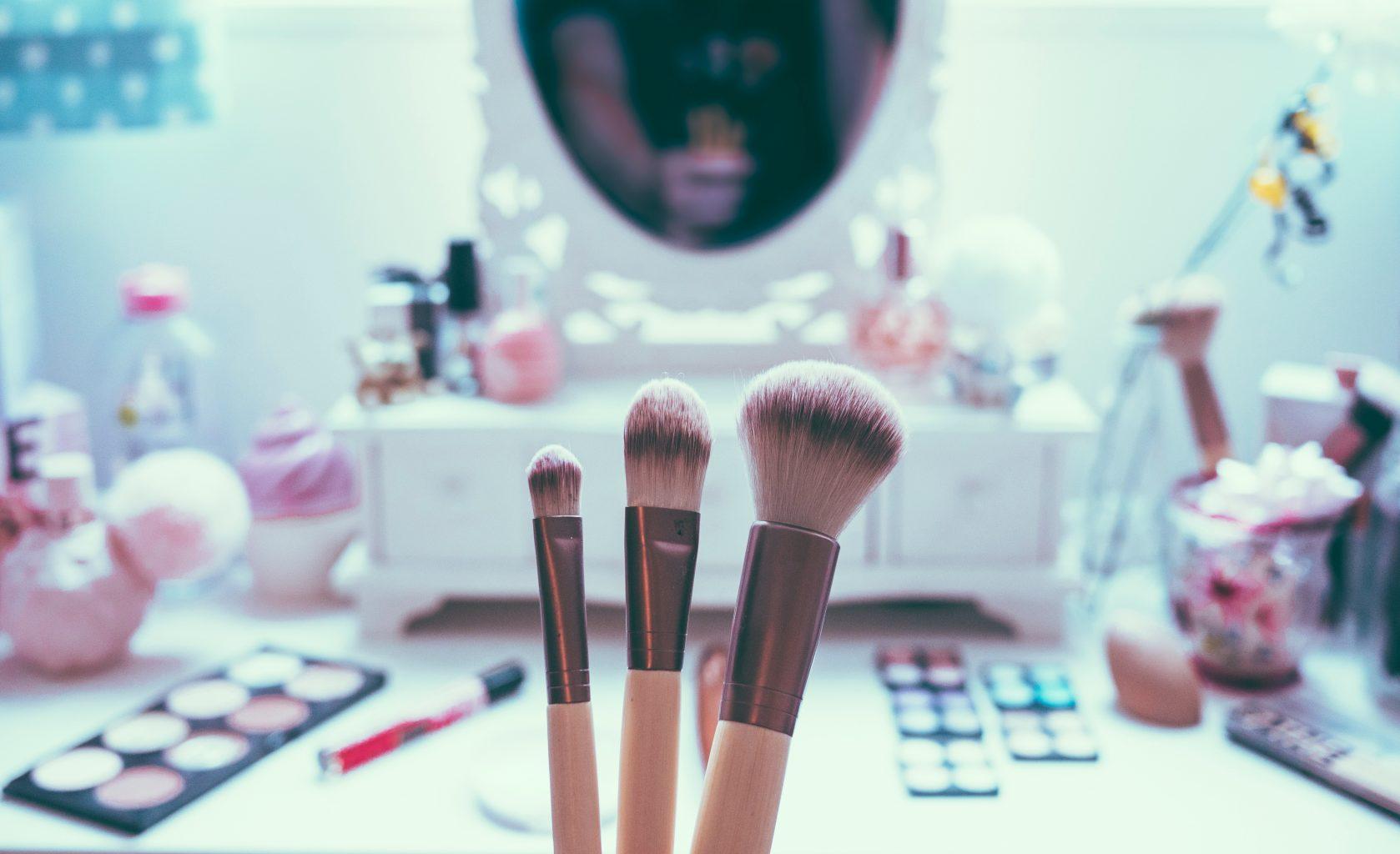 "mirror on a desk with make-up brushes"