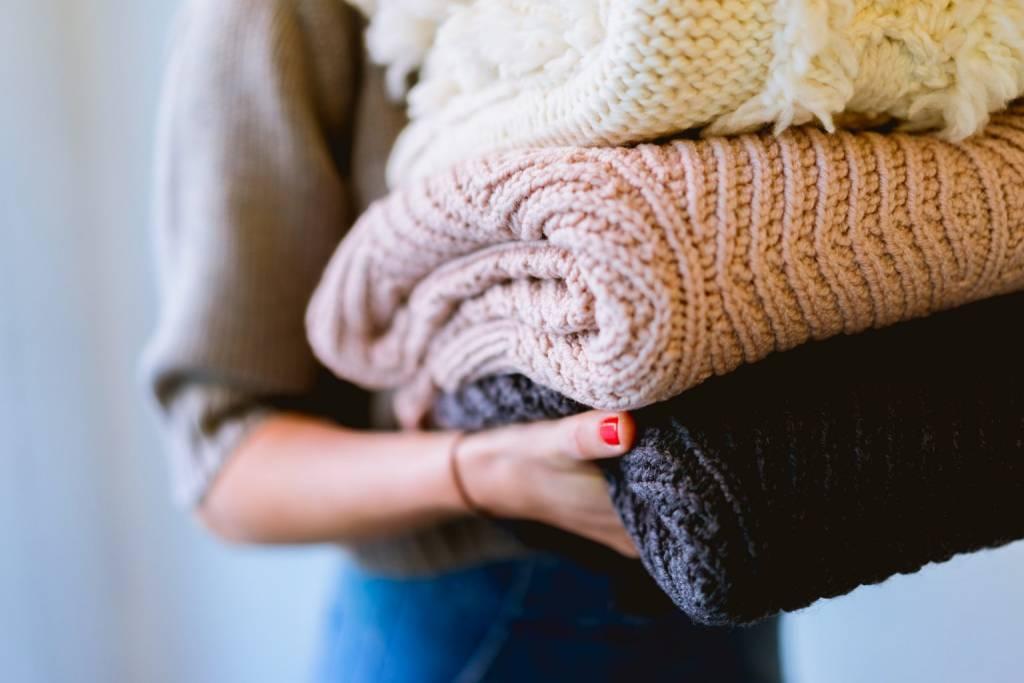 Woman carries a stack of knit blankets