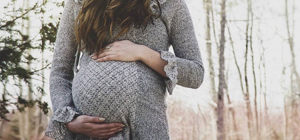 Pregnant woman holds her belly outdoors
